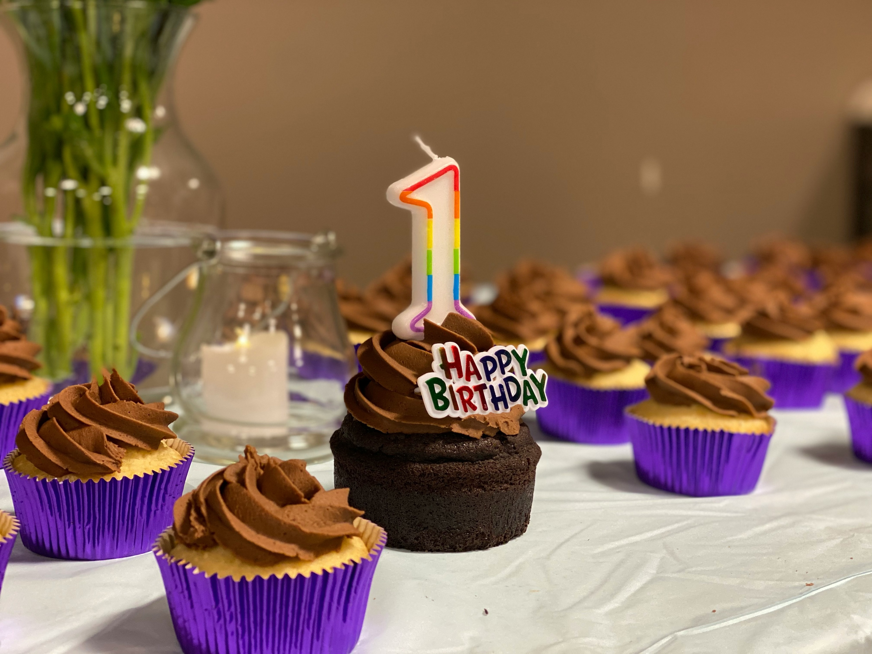 A chocolate cupcake with a happy birthday sign and a giant number one candle.
