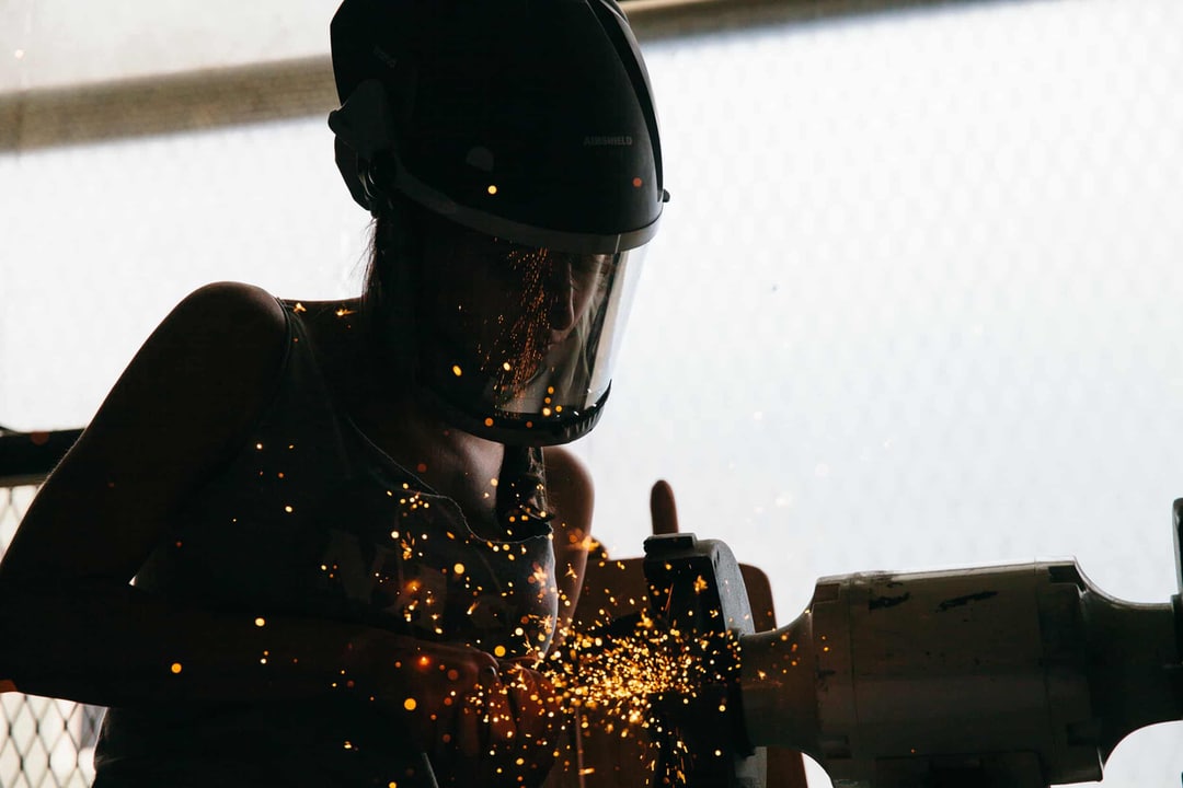 Photograph of a blacksmith working metal at a grinder.